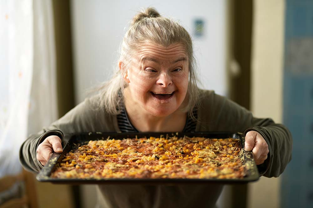 portrait of adult woman with down syndrome holding pizza